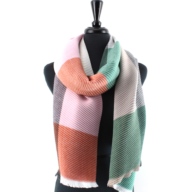 A multicolor striped knit scarf with fringed edges draped on a black mannequin torso against a white background.