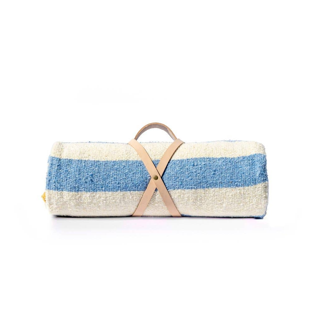 Striped woven blanket rolled up with leather strap on a white background