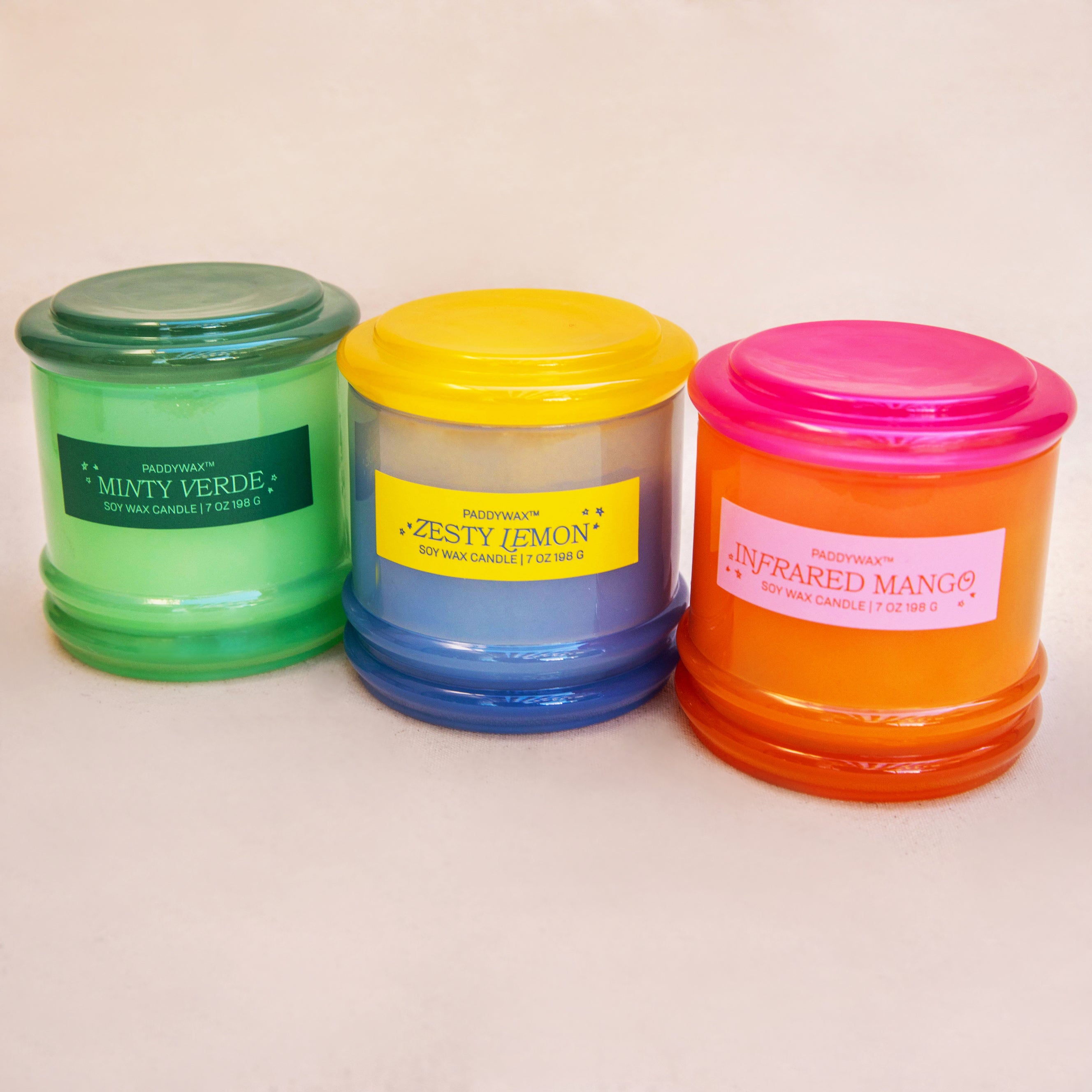 Three scented candles with colorful lids on a light background