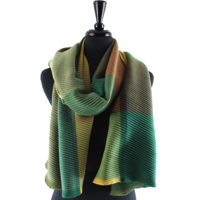 A ribbed knit scarf in shades of green, yellow, and brown, draped on a black mannequin torso against a white background.