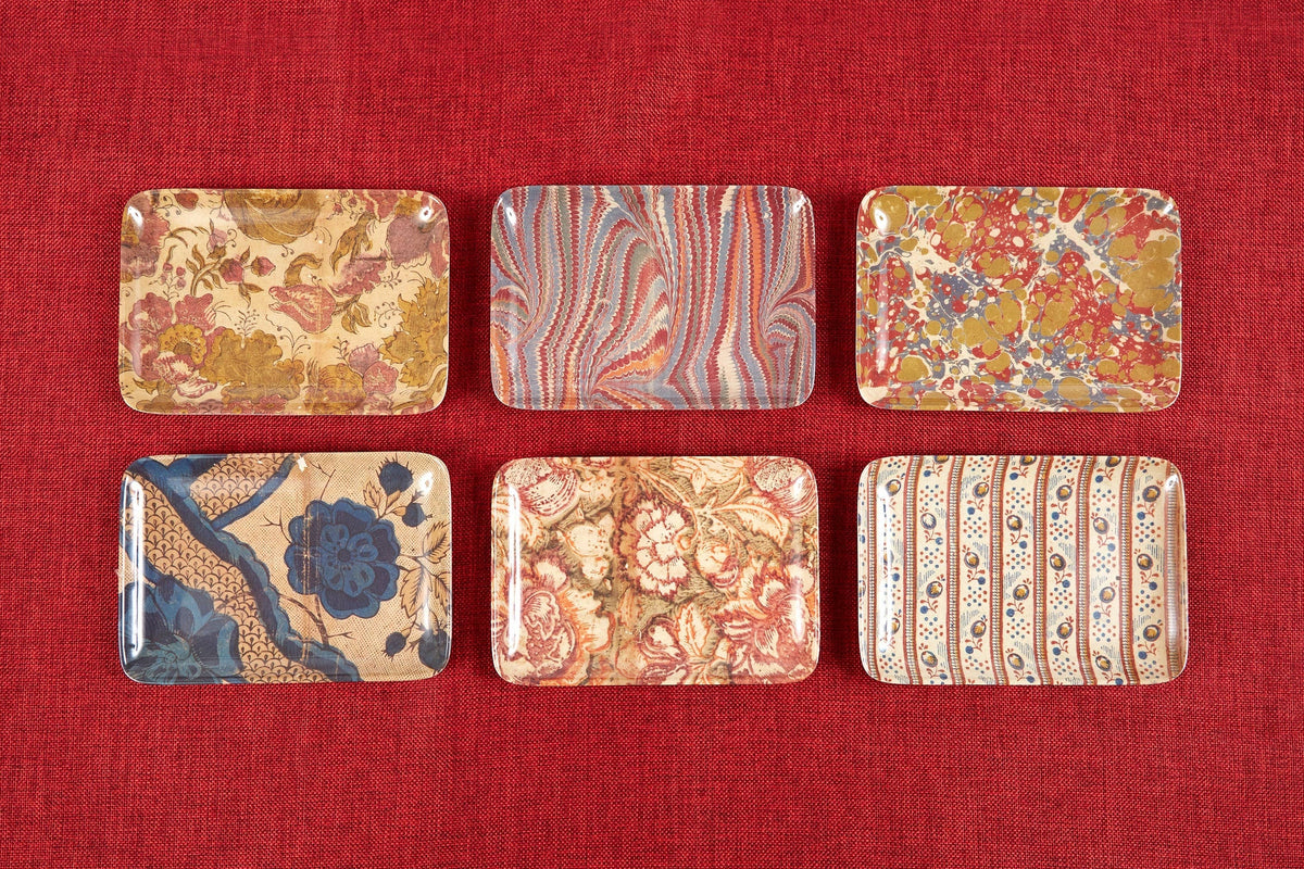 Set of decorative tiles with floral and abstract patterns on a red fabric background