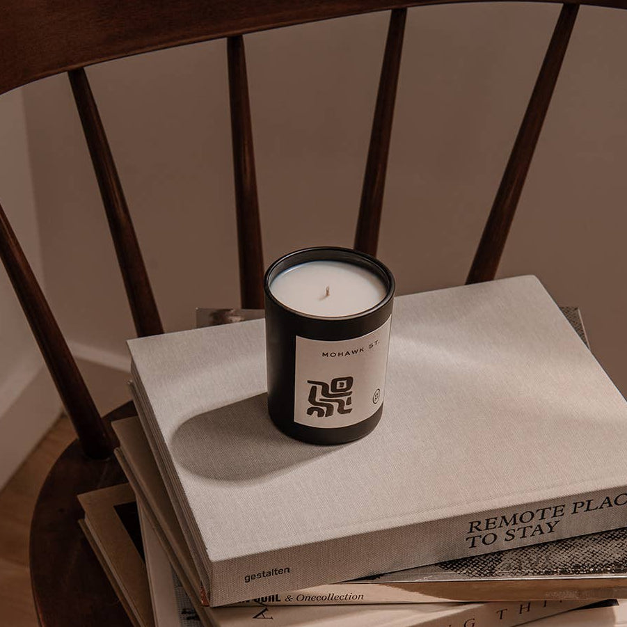 Stack of books with a candle on top, placed on a wooden chair.