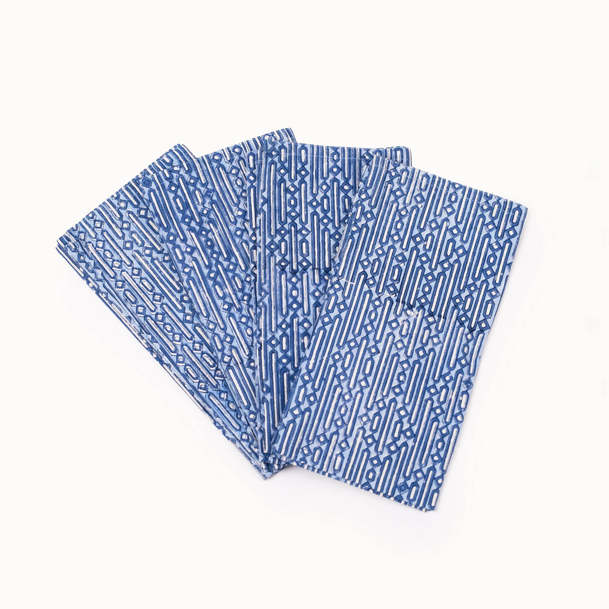A stack of four blue and white patterned rectangular fabric pieces, likely napkins or small tablecloths, arranged in a fan shape on a plain white background.