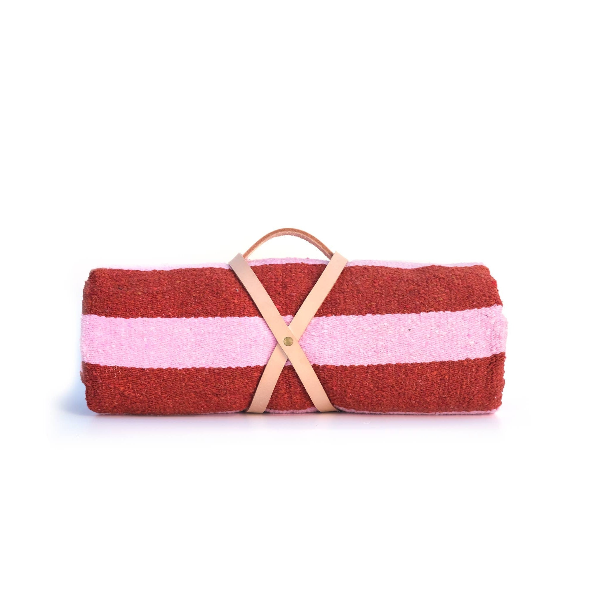 Rolled-up picnic blanket with red and pink stripes and a brown leather strap on a white background