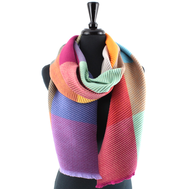 A multicolor striped knit scarf draped on a black mannequin torso against a plain white background.