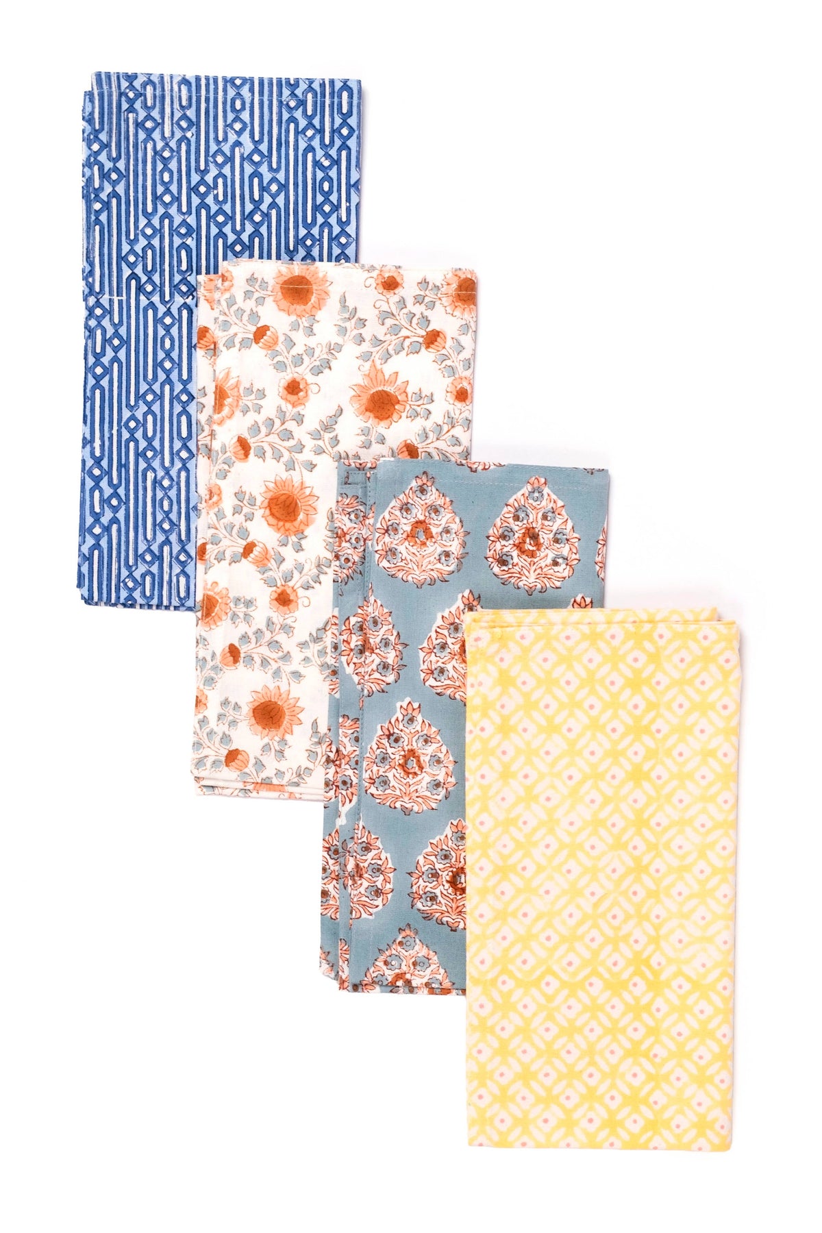 Four folded fabric napkins with different patterns are arranged in a cascading stack on a white background. The napkins feature blue geometric stripes, orange floral motifs on a white background, a dusty blue paisley pattern, and a yellow diamond lattice pattern.