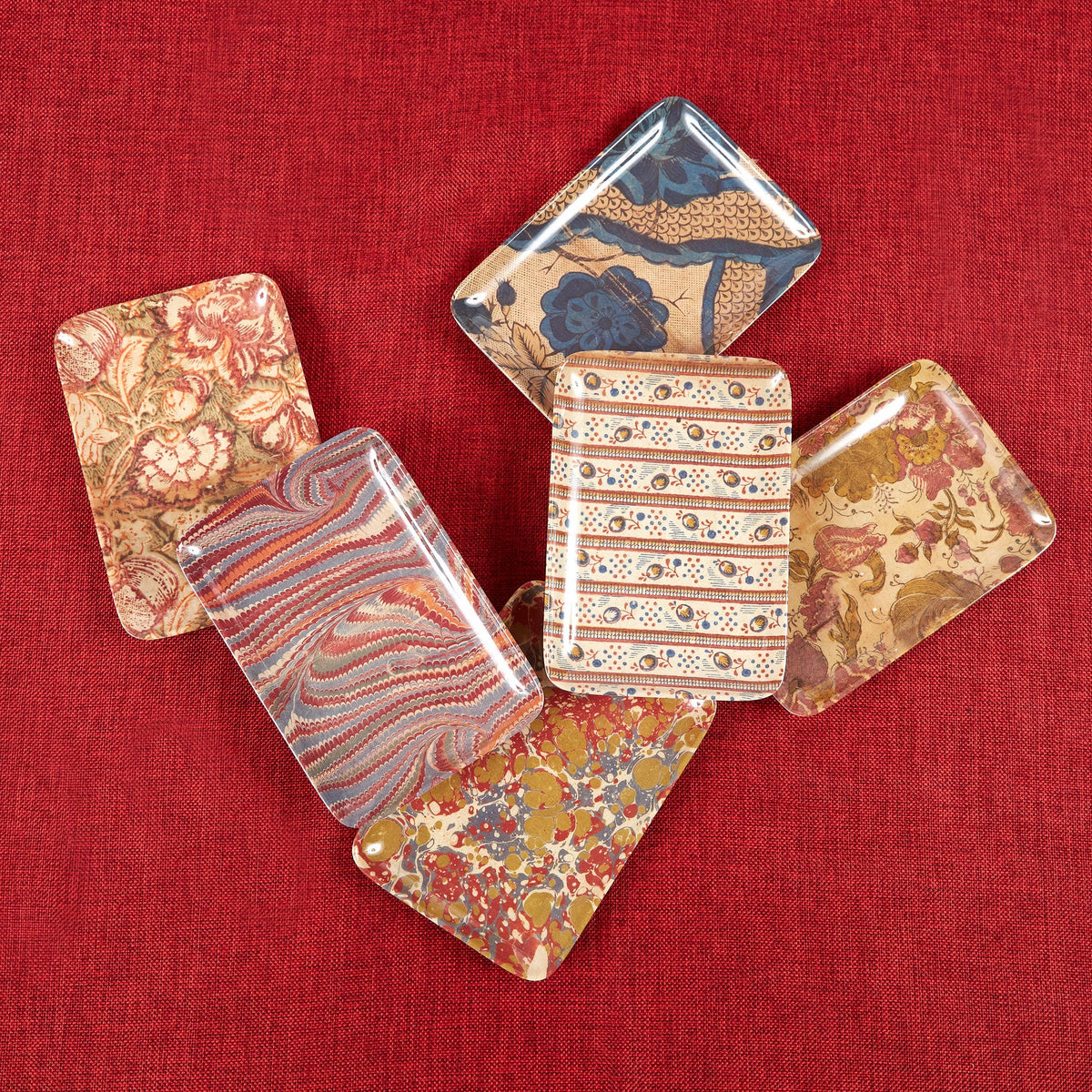 Decorative trays with floral patterns on a red fabric background