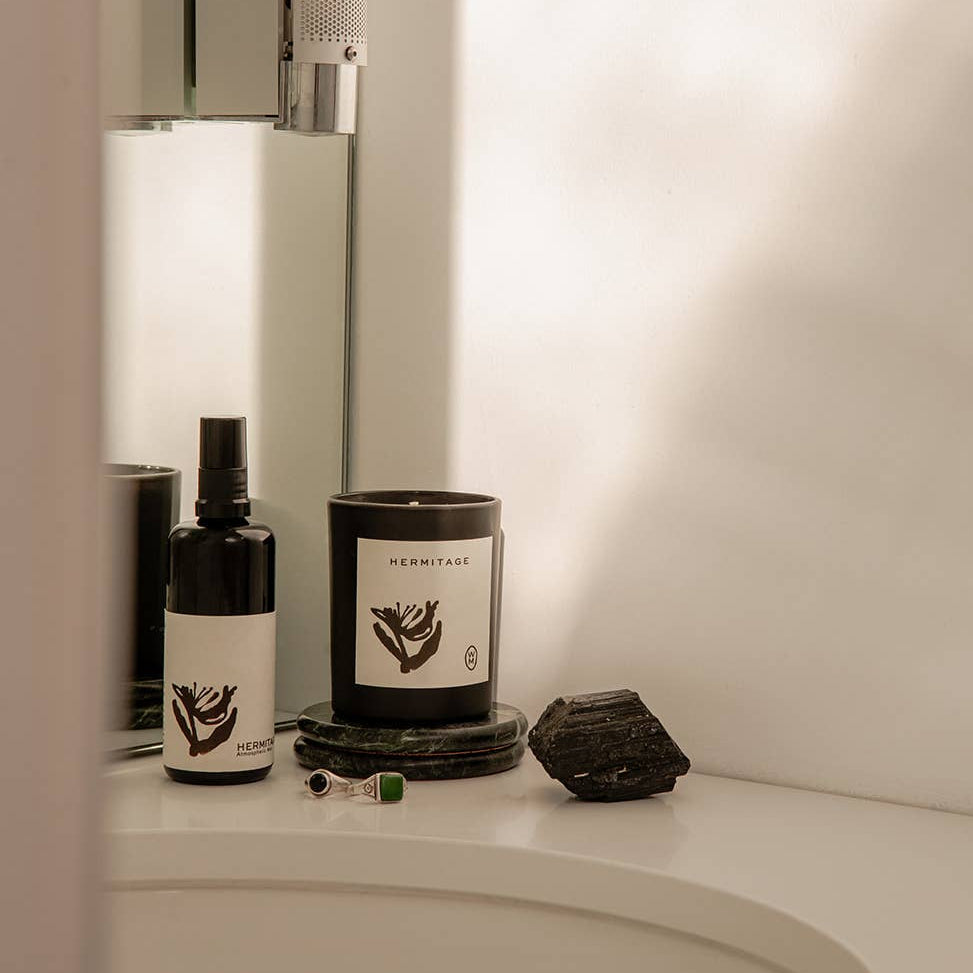 Bathroom counter with skincare products and a candle.