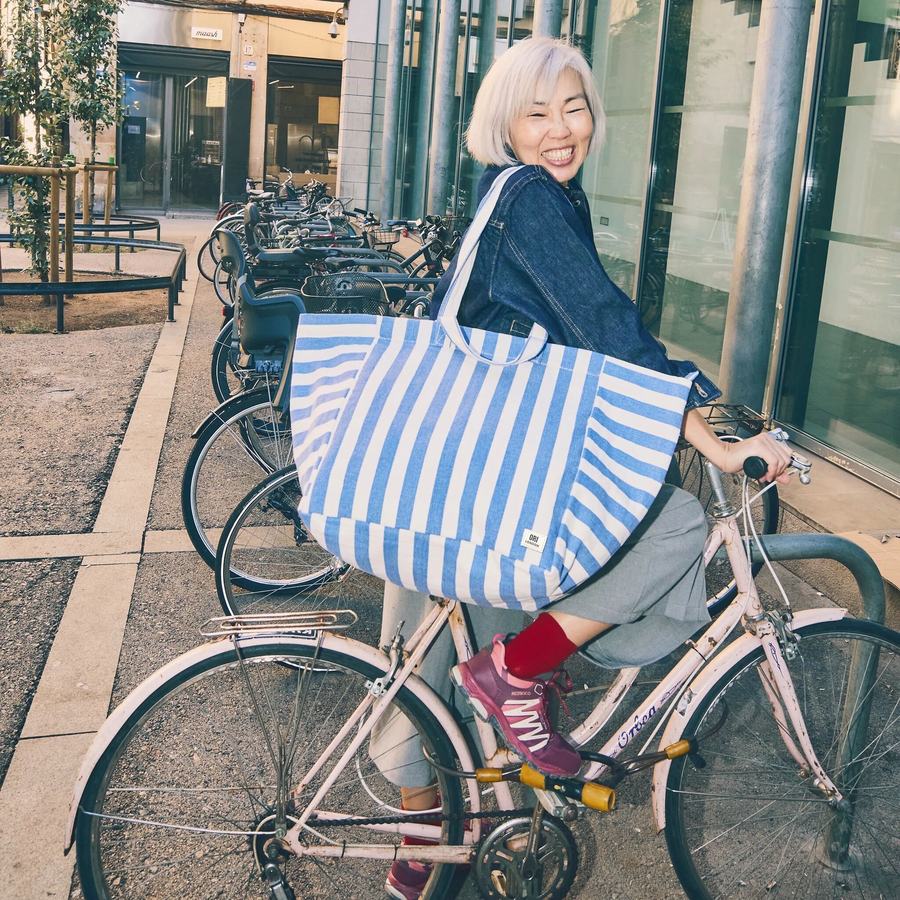 Woman with a blue and white striped bag on a bicycle in an urban setting