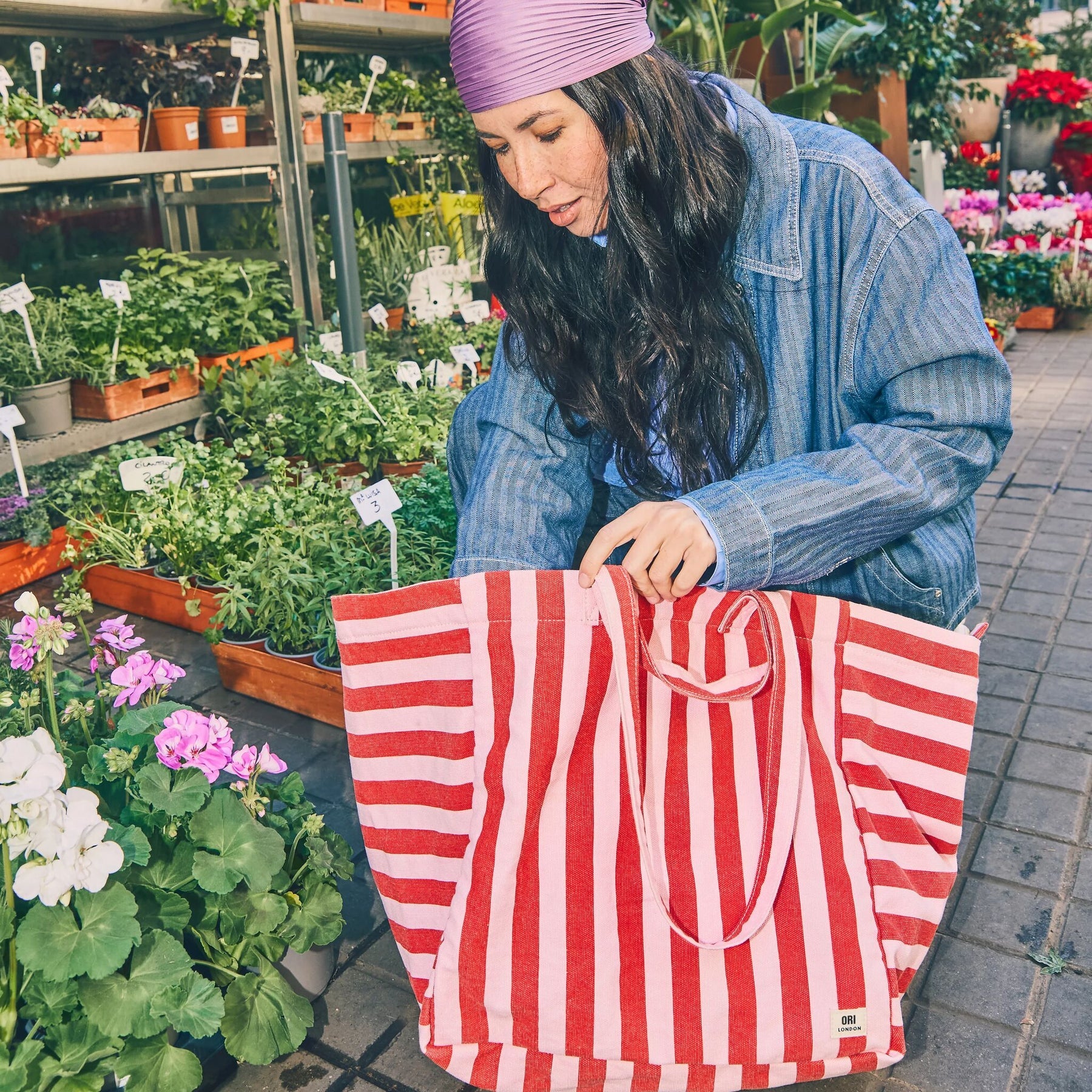 Woman at a plant store holding red and pink stripe tote bag