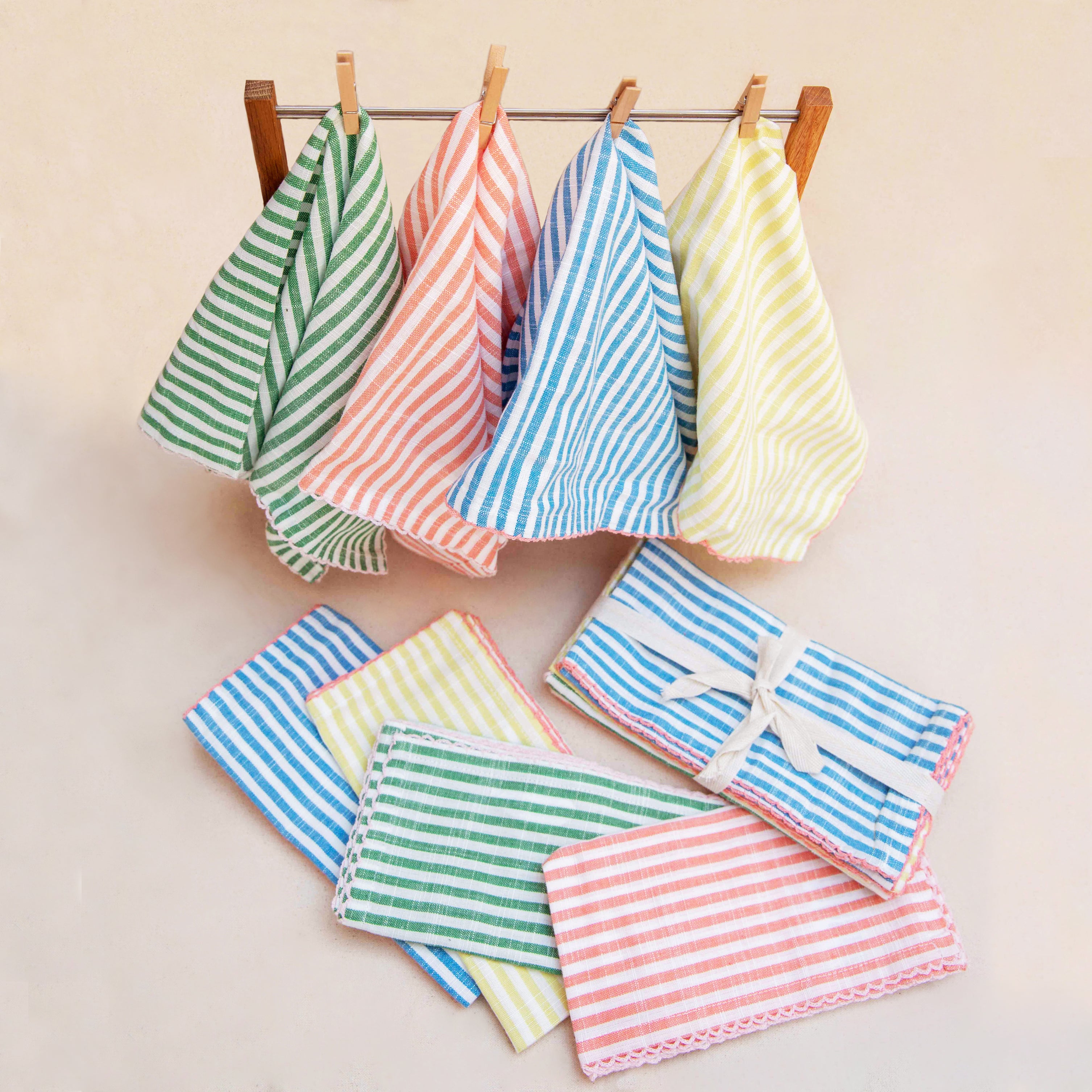 Colorful striped napkins hanging on a rack with additional folded towels on a light background