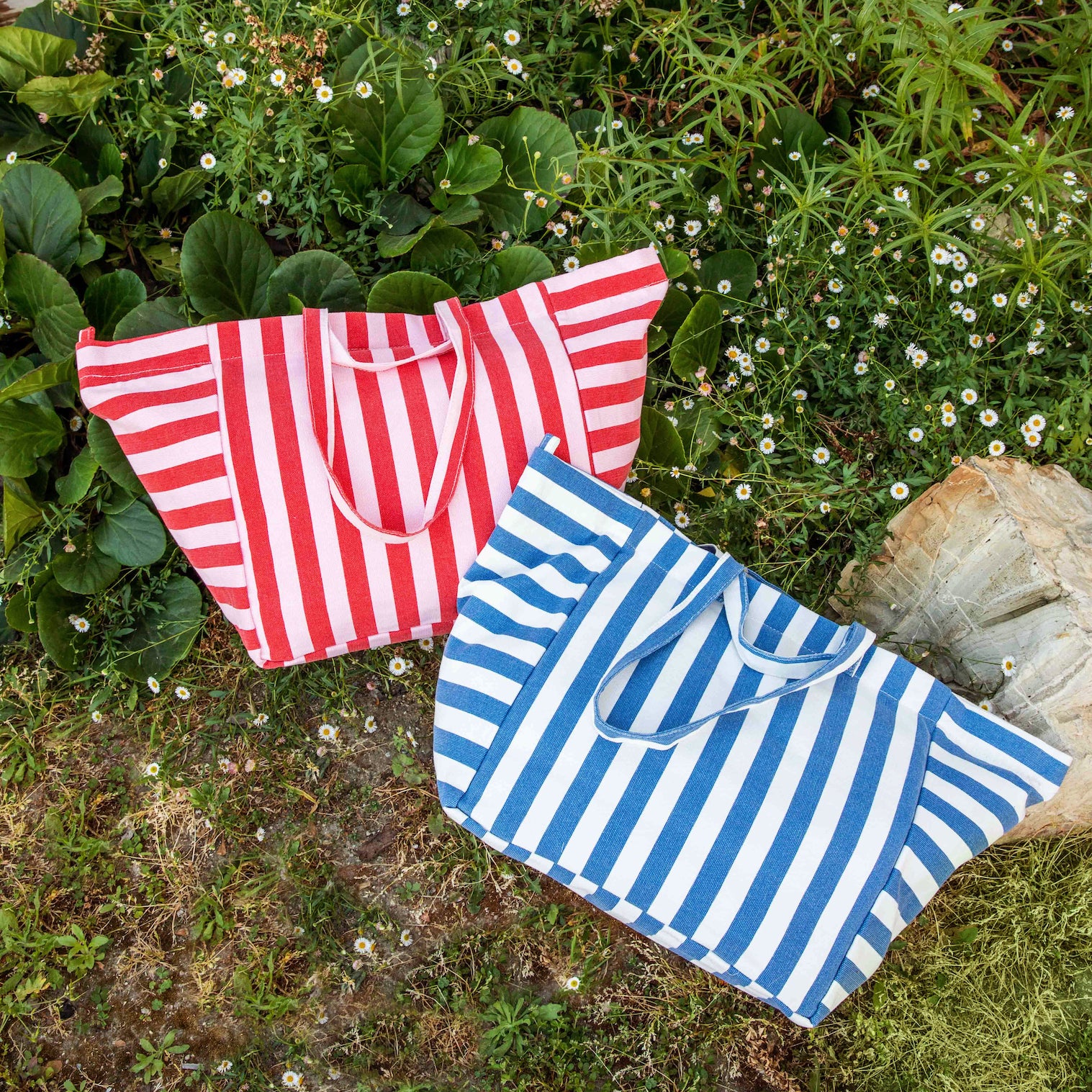 Two striped bags, one red and white, one blue and white, on a grassy background.