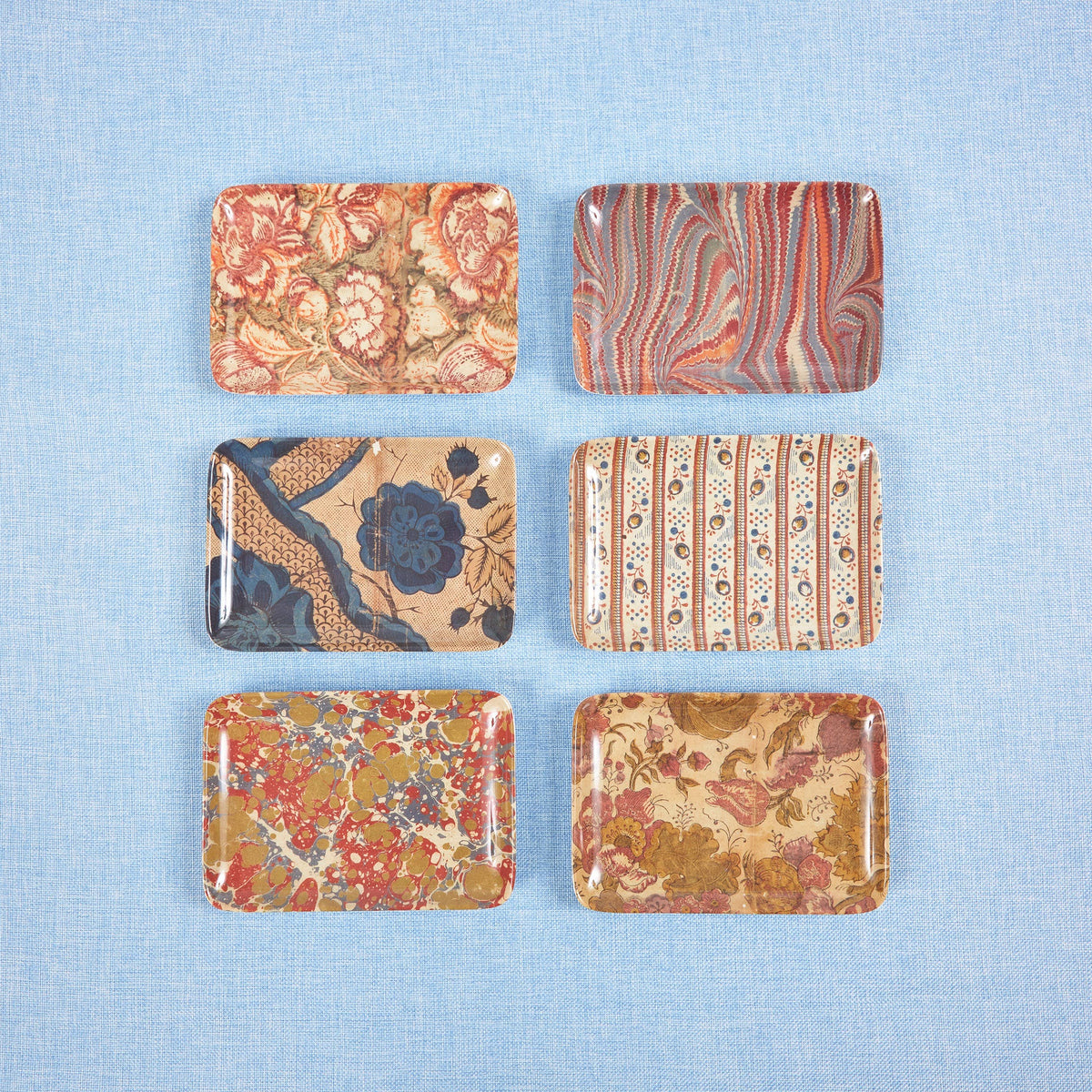 Set of six patterned coasters on a blue textured surface